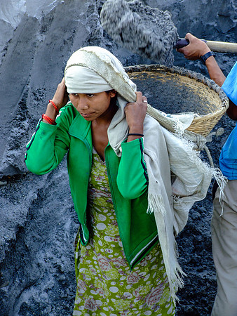 Young woman getting heavy basket of sand filled on her back