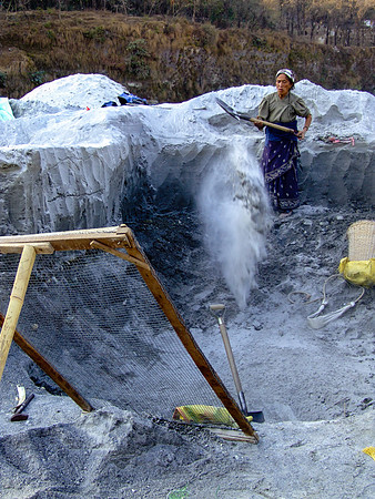 Old woman shoveling sand in the mine