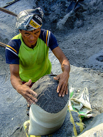 River miner filling a sack with sand