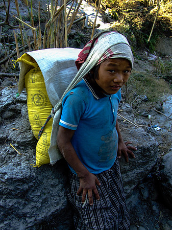 Young boy carrying a sack of sand from a river mine